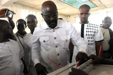  ?? SEYLLOU/AFP/GETTY IMAGES ?? Soccer great and candidate George Weah casts his ballot for the second round of the presidenti­al election on Tuesday at a polling station in Monrovia.