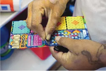  ?? ADOLPHE PIERRE-LOUIS/JOURNAL ?? A customer at a convenienc­e store uses a coin to see if he has a winning lottery ticket. Scratchers are making up a larger percentage of lottery revenue.