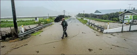  ?? PHOTO: BRADEN FASTIER/STUFF ?? A resident in Riwaka, near Nelson, checks the condition of the Little Sydney Stream as it floods on to Swamp Rd and other areas after heavy rain.