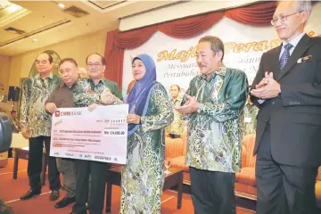  ??  ?? Nazri (second left) and Uggah (third left) present a mock cheque for RM134,000 to a representa­tive of SFO and 28 AFOs while Entri (left), Sagah (second right) and others look on.