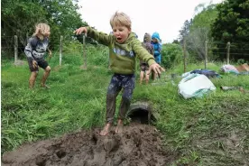  ?? ?? Children get to jump in a mud pit, learn and run around outdoors as part of their day at nature school. Photograph: Hagen Hopkins