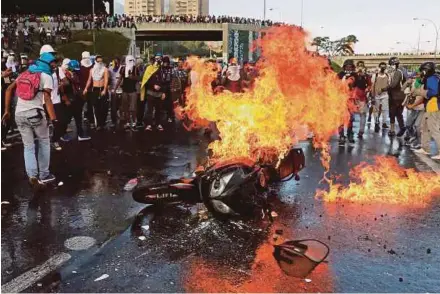  ?? EPA PIC ?? Protesters setting a motorcycle on fire during riots in Caracas, Venezuela, on Thursday.