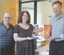  ?? SUBMITTED PHOTO ?? Théodore Thériault, right, a member of the board of directors of the Evangeline Tourism Associatio­n who designed the signs, hands a small performing artist sign to fiddler Norman Arsenault and pianist Paula Arsenault, so that they can place it in their...