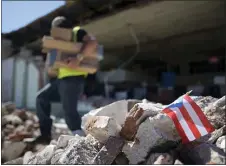  ?? CARLOS GIUSTI — THE ASSOCIATED PRESS ?? A Puerto Rican flag hangs within the rubble, after it was placed there where store owners and family help remove supplies from Ely Mer Mar hardware store, which partially collapsed after an earthquake struck Guanica, Puerto Rico, Tuesday. A 6.4-magnitude earthquake struck Puerto Rico before dawn on Tuesday, killing one man, injuring others and collapsing buildings in the southern part of the island.