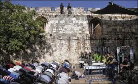  ?? MAHMOUD ILLEAN / AP ?? Israeli police stand guard as Muslim men pray outside the Al Aqsa Mosque compound in Jerusalem on Sunday. Newly installed metal detectors are at right.