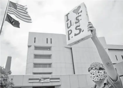  ?? KARL MERTON FERRON/BALTIMORE SUN ?? James Baldwin holds a sign supporting the U.S. Postal Service during a rally Saturday at the main post office in Baltimore.