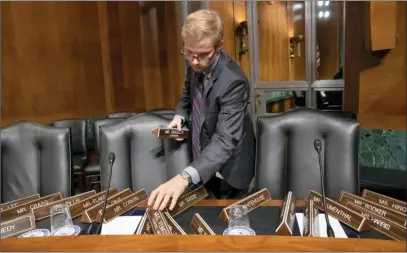  ?? The Associated Press ?? Senate Judiciary Committee staffer Nathan Young sets out nameplates for members of the panel who will hear testimony from Christine Blasey Ford about her allegation of sexual assault against Supreme Court nominee Brett Kavanaugh.