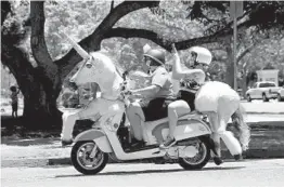  ??  ?? A scooter rider near Balboa Park shows off the unicorn attached to the front and back of the vehicle.