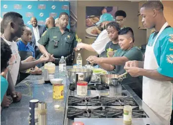  ?? MICHAEL LAUGHLIN/SUN SENTINEL ?? Children from various local Police Athletic Leagues join Dolphins players in making Caesar salads during the Dolphins Kids Cook-Off event Tuesday at the Publix Aprons Cooking School in Plantation.