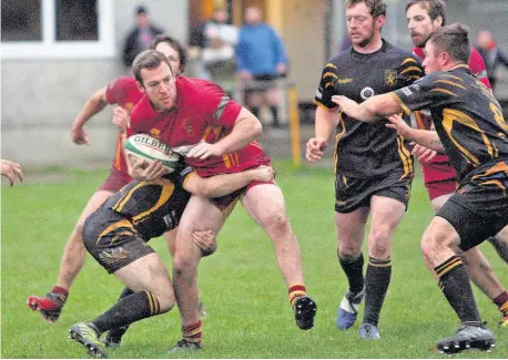  ??  ?? Caernarfon’s Carwyn Roberts tries to break away from these Bethesda tackles.