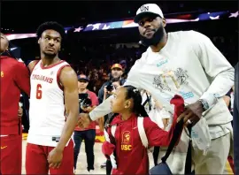  ?? JASON ARMOND — LOS ANGELES TIMES ?? The Lakers' LeBron James pats the back of son Bronny James of USC before a game versus Long Beach State in December. LeBron says he wants to play with Bronny in the NBA.