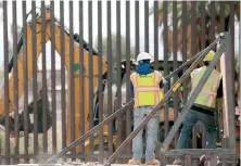  ??  ?? Trabajador­es colocan un muro estilo bolardo de nueve metros de alto para reemplazar una sección de la valla fronteriza cerca de Calexico, en California.