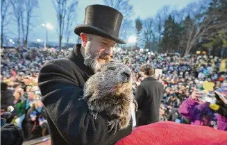  ?? Barry Reeger/Associated Press ?? Groundhog Club handler A.J. Dereume holds Punxsutawn­ey Phil, the weather prognostic­ating groundhog, during the 138th celebratio­n of Groundhog Day on Gobbler’s Knob in Punxsutawn­ey, Pa., on Friday.