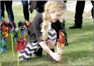  ?? LYNN KUTTER ENTERPRISE-LEADER ?? Bailey Brown, 7, of Lincoln, helps place pinwheels in the ground in front of Prairie Grove City Hall. Each pinwheel represents a child who was abused in Washington County.