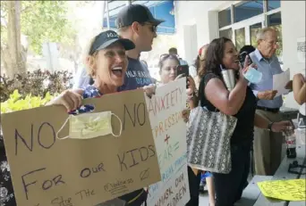  ?? Marta Lavandier/Associated Press ?? Joann Marcus, of Fort Lauderdale, Fla., left, protests mask mandates as she listens during the Broward School Board’s emergency meeting on Wednesday.