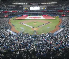  ?? FRANK GUNN/ THE CANADIAN PRESS ?? An enormous Canadian flag is unfurled as fans and players stand for the national anthems before the start of the Blue Jays’ home opener Friday night at Rogers Centre.