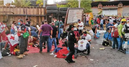  ?? Sergio Hernandez / Tribune News Service ?? Police and rescue workers help survivors and assess the dead after an accident in which at least 55 migrants died in Tuxtla Gutierrez, Mexico. Scores also were injured after a trailer in which they were secretly traveling crashed into a retaining wall.