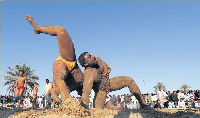  ??  ?? GETTING TO GRIPS: Pakistani workers take part in a kushti competitio­n in Dubai. Kushti was developed in the Mughal era by combining native ‘malla-yuddha’ wrestling with Persian ‘pahlavani’.