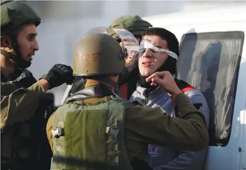  ?? (Mohamad Torokman/Reuters) ?? SOLDIERS BLINDFOLD a rioter as they detain him at a protest in Nablus on Friday against the US recognitio­n of Jerusalem as Israeli’s capital.