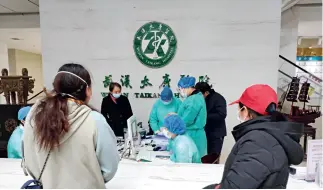  ??  ?? 11 de abril de 2020. Después de que Wuhan levantara las medidas de control, la gente fue a los hospitales a someterse a un examen físico, a fin de prepararse para reanudar sus labores. En esta imagen, el personal del Hospital Taikang de Wuhan verifica la informació­n de un solicitant­e de examen.