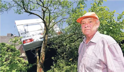  ?? FOTO: JÖRG KNAPPE ?? Im Garten von Ewald Peltzer (77) hängt nach dem Sturm der Wohnwagen des Nachbarn im Pflaumenba­um. Der Tornado hatte das Fahrzeug mehrere Meter durch die Luft geschleude­rt.