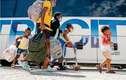  ?? Mark Mulligan / Staff photograph­er ?? A family walks to a charter bus that will evacuate them from Galveston Island to Austin ahead of Hurricane Laura’s landfall.