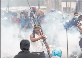  ?? Dolores Ochoa The Associated Press ?? An anti-government demonstrat­or stands in the middle of clouds of tear gas in Quito, Ecuador, on Friday. The protesters want fuel subsidies restored.