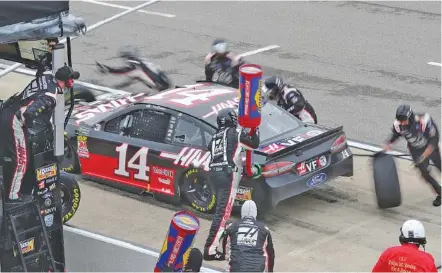  ?? THE ASSOCIATED PRESS ?? The pit crew for the Stewart-Haas Racing No. 14 Ford adds gas and changes tires as Clint Bowyer waits to head back onto the track Sunday.