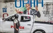  ??  ?? A police officer in Port-au-Prince, in front of a mural of Moïse