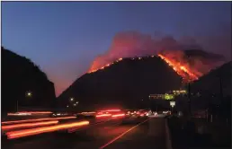  ?? LOS ANGELES TIMES ?? Traffic continues as flames roar up a steep hillside near the Getty Center in Los Angeles.