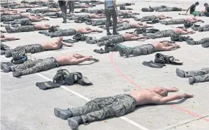  ??  ?? LEFT Trainees are ordered to lie on the hot concrete ground with their faces exposed to the glaring sunlight.