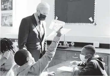  ?? MANUEL BALCE CENETA/AP ?? President Joe Biden stops to look at a student’s project Friday as he tours Brookland Middle School in Washington. Biden has encouraged every school district to promote vaccines to protect students as they return to school.