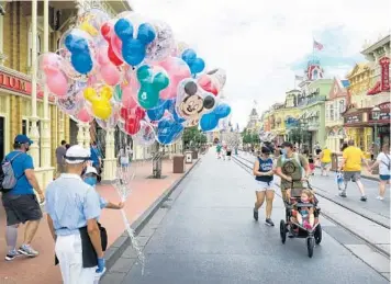  ?? JOE BURBANK/ORLANDO SENTINEL PHOTOS ?? A less-populated Main Street, U.S.A. is part of the Magic Kingdom experience. The Walt Disney World theme park reopened from its coronaviru­s shutdown in mid-July.