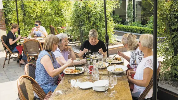  ?? PHOTOS BY LAURA MORTON / SPECIAL TO THE CHRONICLE ?? A group of relatives eat lunch at Pietro’s Trattoria in the outdoor courtyard, where the restaurant grows some of the vegetables and herbs used in their dishes.