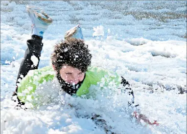  ?? JEFF VORVA/DAILY SOUTHTOWN ?? Beverly resident Nolan Baudo concludes his run through a Polar Cannon spray of cold water with a headfirst dive into the snow Tuesday at Marist High School. Baudo, a Marist sophomore, helped get the word out to help raise money for Special Olympics Chicago.