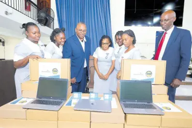  ?? CONTRIBUTE­D PHOTOS ?? Nurse Owen Gregory, senior Internatio­nal heritage liaison for AdventHeal­th, is flanked by Northern Caribbean University (NCU) nursing students as Pastor Everett Brown (right), board chair for AMH, NCU and GSI Foundation, looks on as they examine samples of the 110 HP laptops and oximeters presented by AdventHeal­th, NCU and GSI Foundation during a handover ceremony last Wednesdady at the Kencot SDA Church.