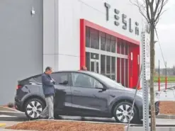  ?? ?? Below: A customer checks out a Tesla vehicle at the company’s new showroom and service center.