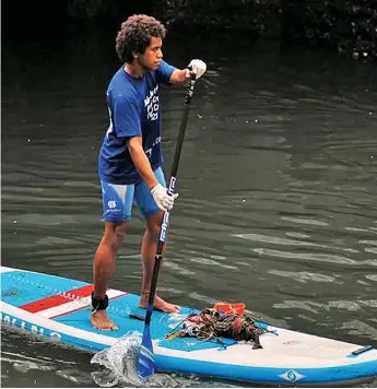  ?? ?? Epeli Lalagavesi colleting rubbish on his Stand-up paddle board.