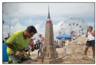  ?? AP/MARY ALTAFFER ?? Gilbert Ortega of Newark, N.J., builds a sand replica of the Empire State Building on Saturday during the 28th annual Coney Island Sand Sculpting Contest in New York.