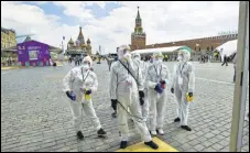 ??  ?? Volunteers in protective gear gather to clean an area of an outdoor book market set up at Red Square in Moscow on Saturday. AP