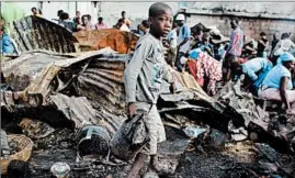  ?? RICARDO ARDUENGO / AP ?? A boy walks Monday through the ruins of a market that was gutted overnight by a fire in the Port-au-Prince suburb of Petionvill­e where hundreds of poor vendors sell vegetables, clothes and other wares.