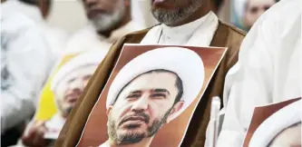  ??  ?? AZ ZINJ: A Bahraini man holds a placard bearing the portrait of Sheikh Ali Salman, head of the Shiite opposition movement Al-Wefaq, during a protest against his arrest, at Al wefaq headquarte­r building, in the village of Zinj on the outskirts of the...