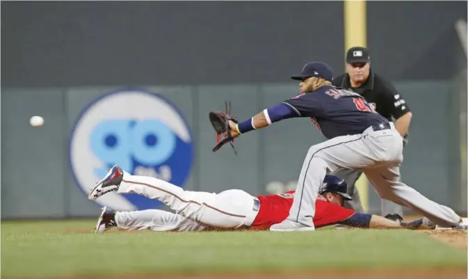  ??  ?? MINNEAPOLI­S: Cleveland Indians first baseman Carlos Santana, front right, waits for the throw as Minnesota Twins’ Brian Dozier, left, dives safely back to first base after Robbie Grossman lined out in the sixth inning of a baseball game Friday, in...