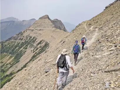  ??  ?? ABOVE: Hikers walk in July along the Continenta­l Divide between Dawson Pass and Pitamakan Pass in Glacier National Park.