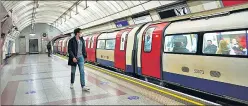  ?? AP ?? A passenger wearing a face mask walks along the undergroun­d train platform in London