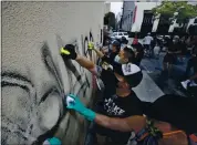  ?? MARCIO JOSE SANCHEZ — THE ASSOCIATED PRESS ?? Volunteers clean graffiti from a store wall Monday in Santa Monica a day after unrest and protests over the death in police custody of George Floyd.