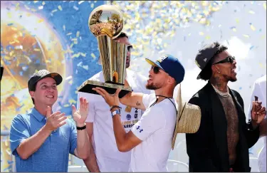  ?? RAY CHAVEZ/TRIBUNE NEWS SERVICE ?? The Golden State Warriors' Stephen Curry holds up the Larry O'Brien NBA Championsh­ip Trophy as majorty owner Joe Lacob applauds at the end of the team's championsh­ip rally in downtown Oakland on Tuesday. Below: Head coach Steve Kerr gets a hug from a fan during the Golden State Warriors' championsh­ip parade.