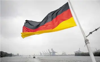  ?? DPA-BILD: CHRISTIAN CHARISIUS ?? Zunehmend seltener Anblick: Eine Deutschlan­dflagge flattert am Heck eines Schiffes vor den Containerb­rücken des Hamburger Hafens.