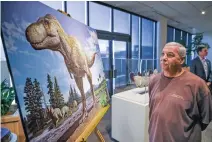  ?? ?? Toby Archuleta, who works with the Sandia Mountain Natural History Center, looks at a rendering of what the Tyrannosau­rus mcraeensis may have looked like.