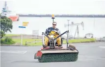  ?? Photo: CHARLOTTE CURD/FAIRFAX NZ ?? A contractor continues to sweep up kernels from a spillage of imported maize on New Plymouth’s Bayly Rd yesterday.